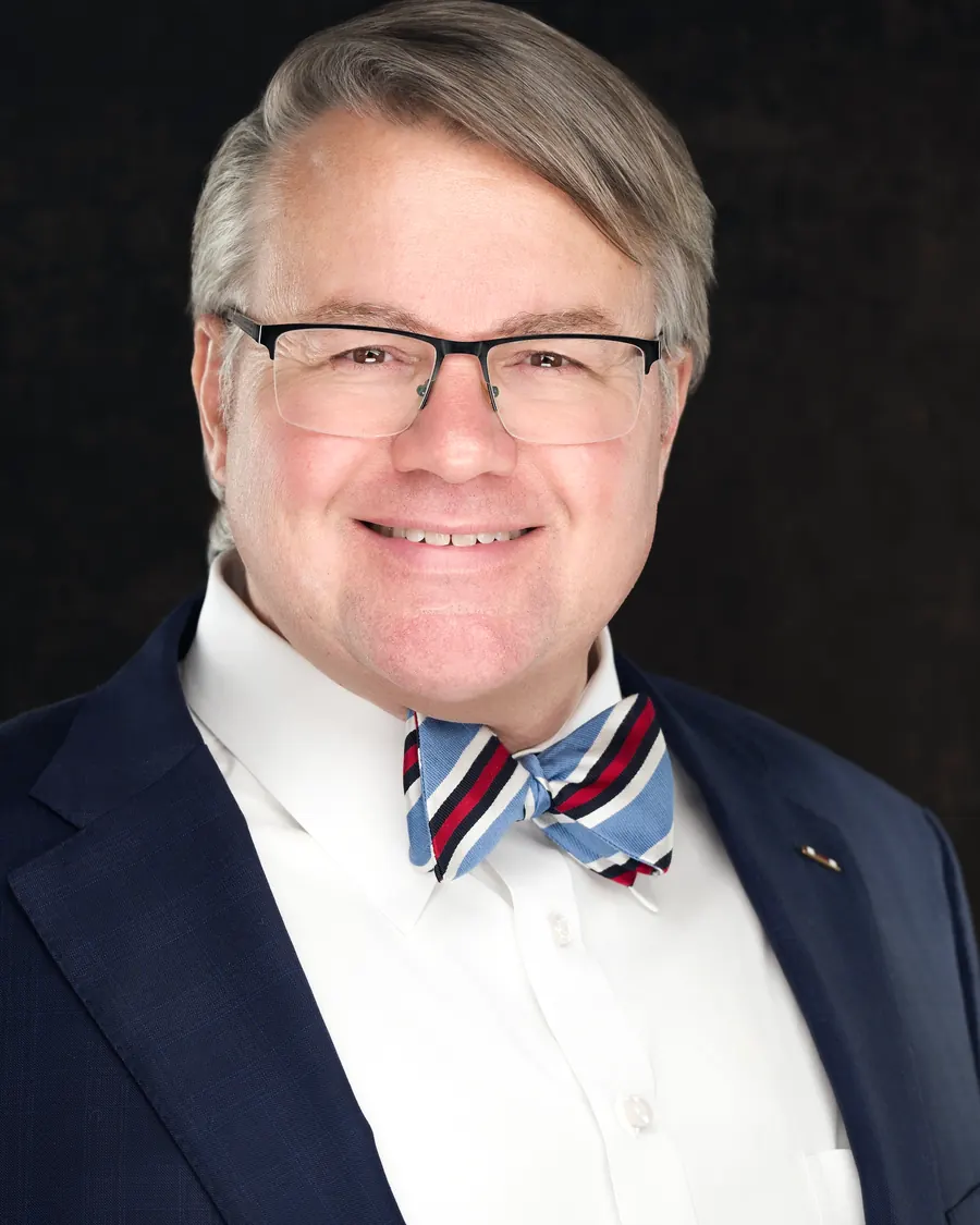 Mark Braswell, smiling in a suit and bow tie
